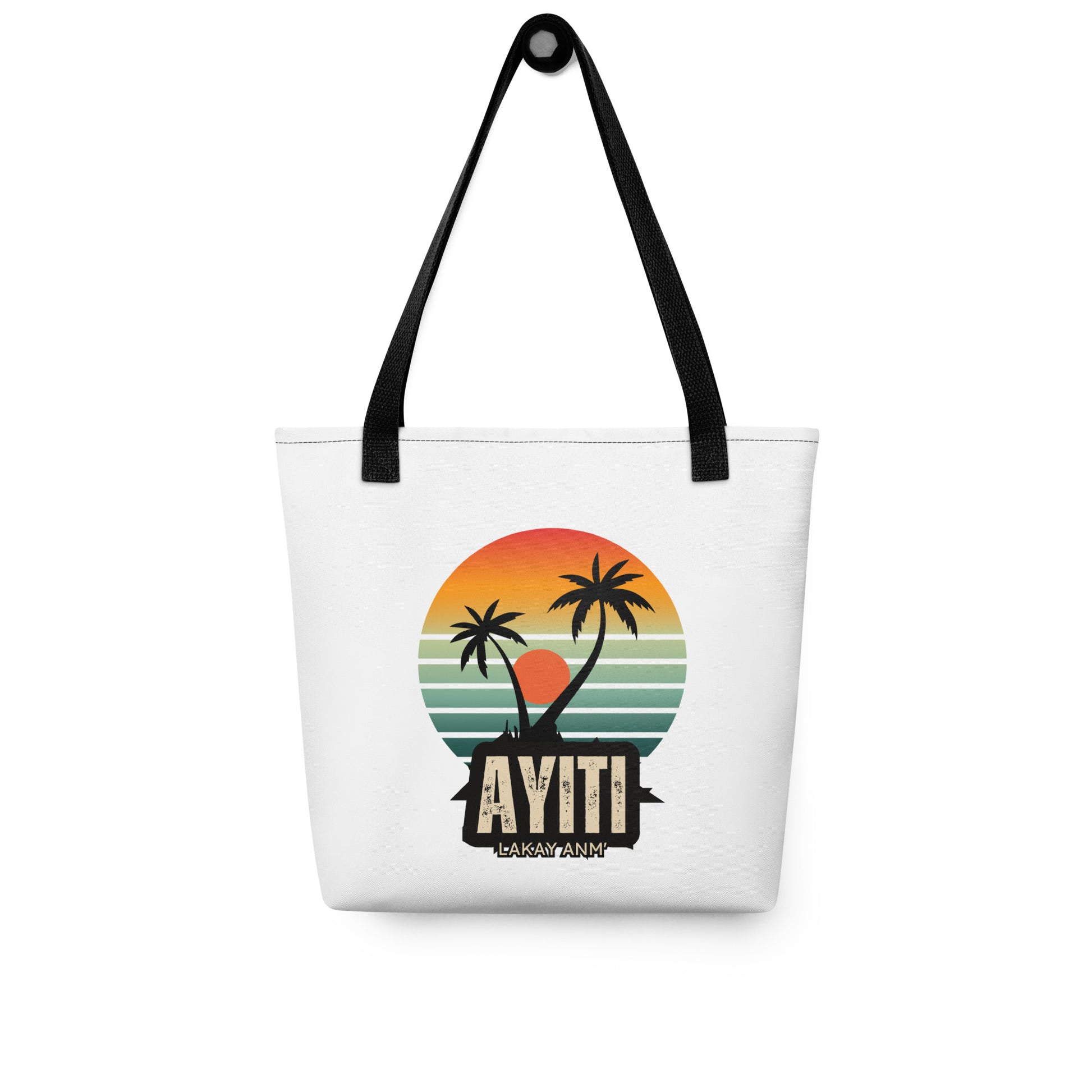 White canvas tote bag with black handles, featuring a circular graphic with an orange and yellow sunset over blue and green stripes, silhouetted by two palm trees. The text 'AYITI' and 'LAKAY ANM'' is below the graphic in a stylized font.