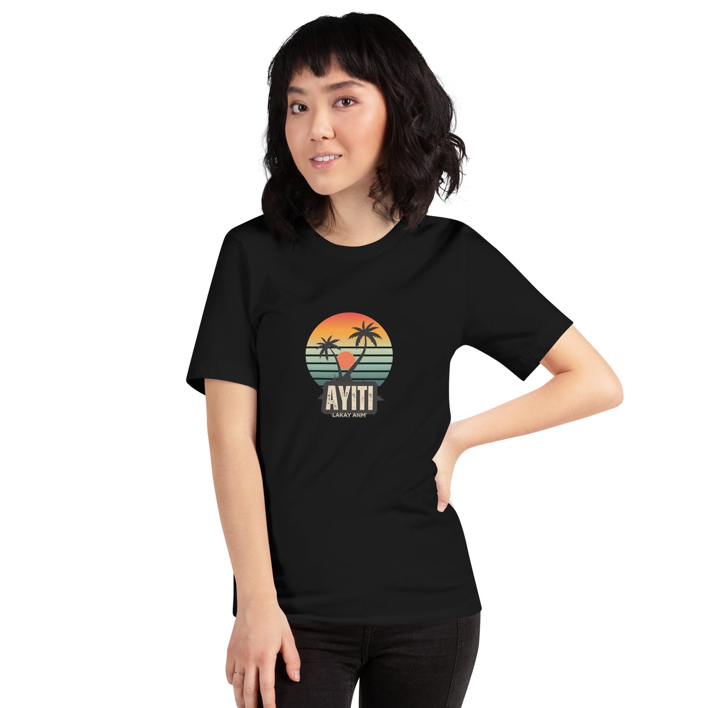 Smiling asian woman wearing a black Bella+Canvas 'Ayiti Lakay Anm'' unisex T-shirt (front view) featuring a vibrant retro sunset graphic with two palm trees silhouetted. White background.