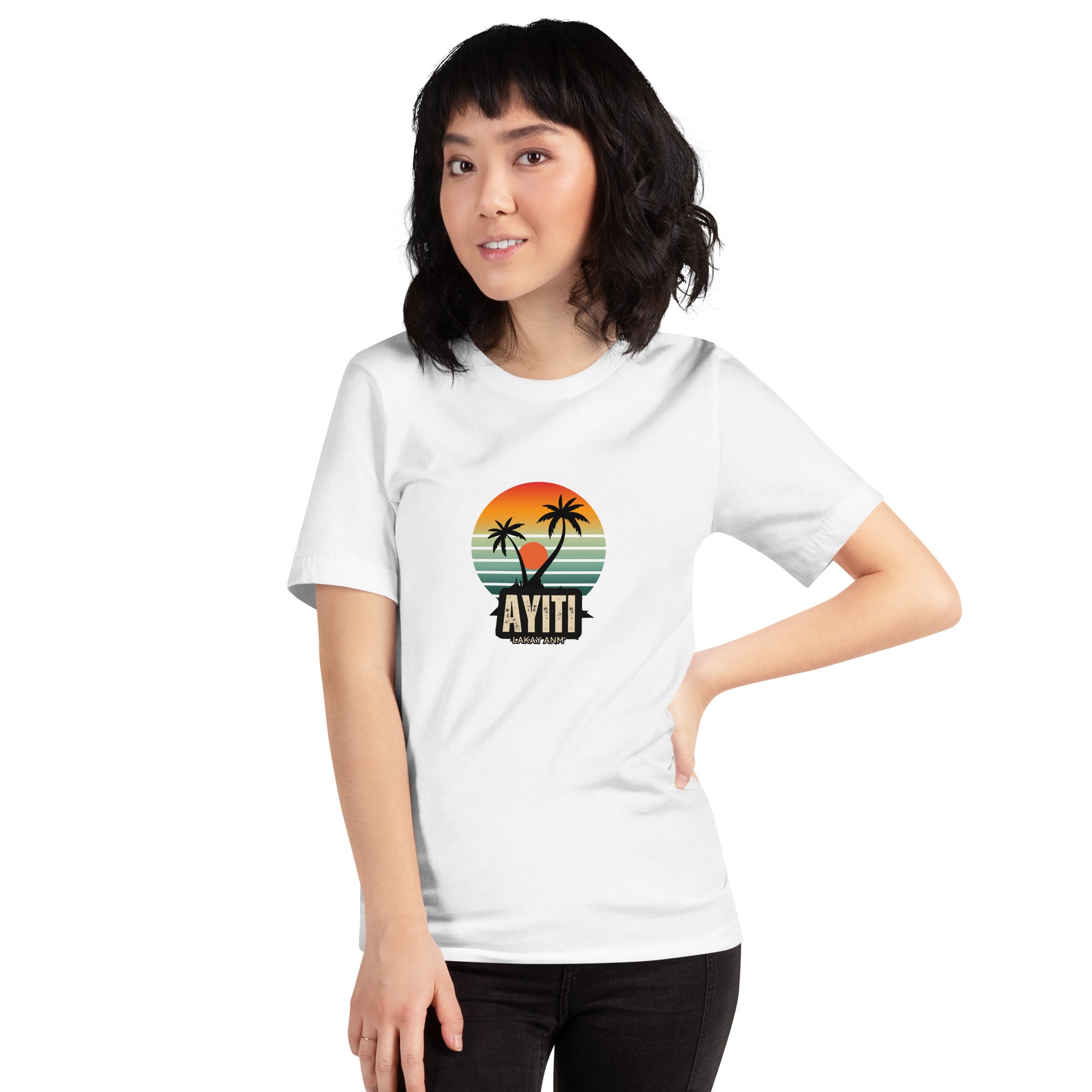 Smiling asian woman wearing a white Bella+Canvas 'Ayiti Lakay Anm'' unisex T-shirt (front view) featuring a vibrant retro sunset graphic with two palm trees silhouetted. White background.