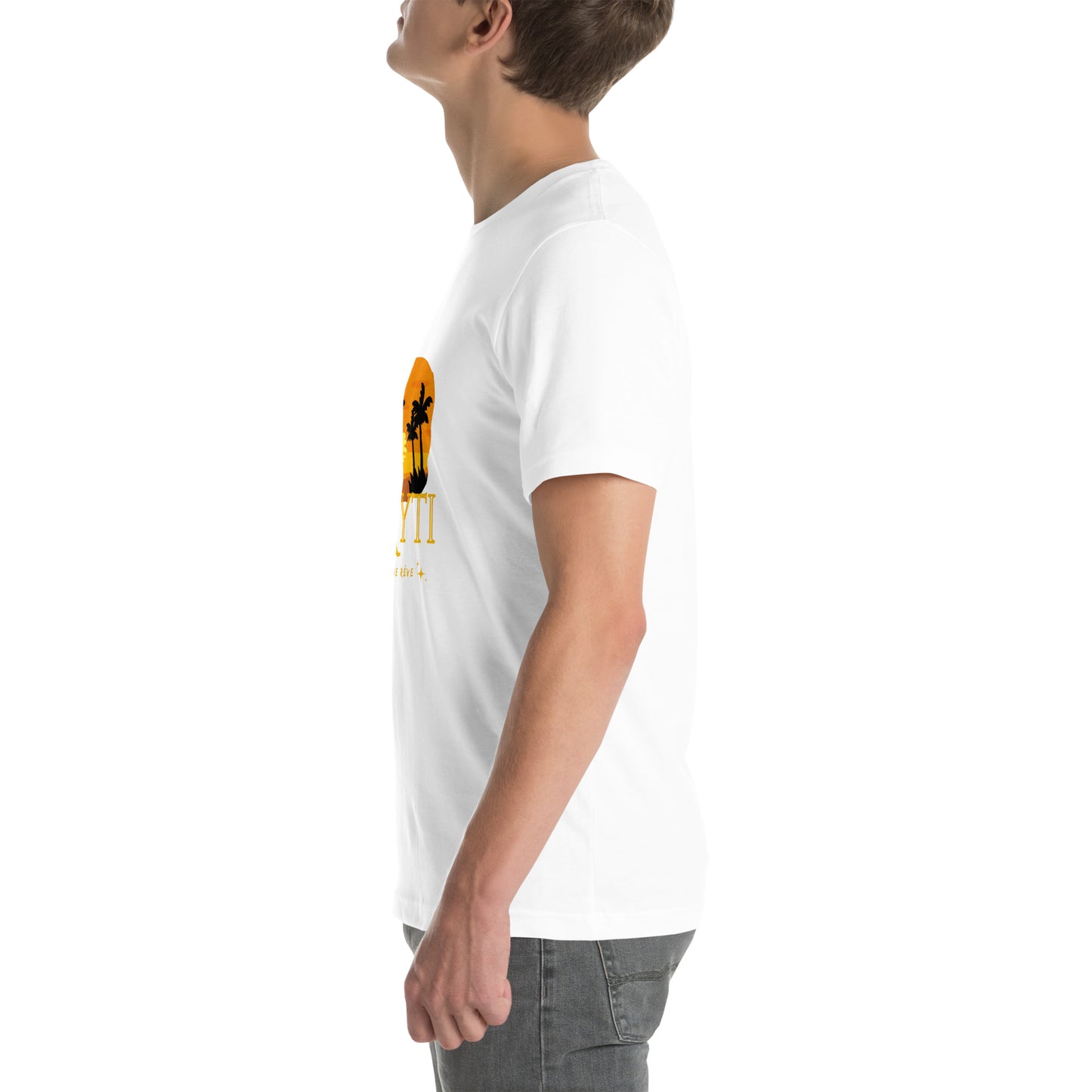 A white man wearing a white Bella+Canvas 'HAYTI PAYS DE RÊVE' unisex T-shirt (left side view) featuring a golden hour sunset graphic with palm trees and twinkling stars. White background.