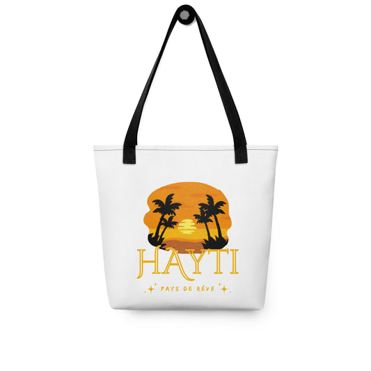 White canvas tote bag with black handles, featuring a golden and orange sunset graphic with silhouetted palm trees and the text 'HAYTI' and 'PAYS DE RÊVE' with small starburst accents.
