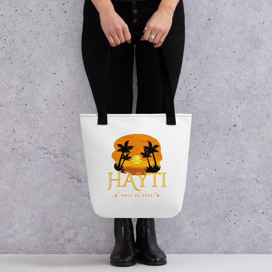 White canvas tote bag with black handles, featuring a golden and orange sunset graphic with silhouetted palm trees and the text 'HAYTI' and 'PAYS DE RÊVE' with small starburst accents.