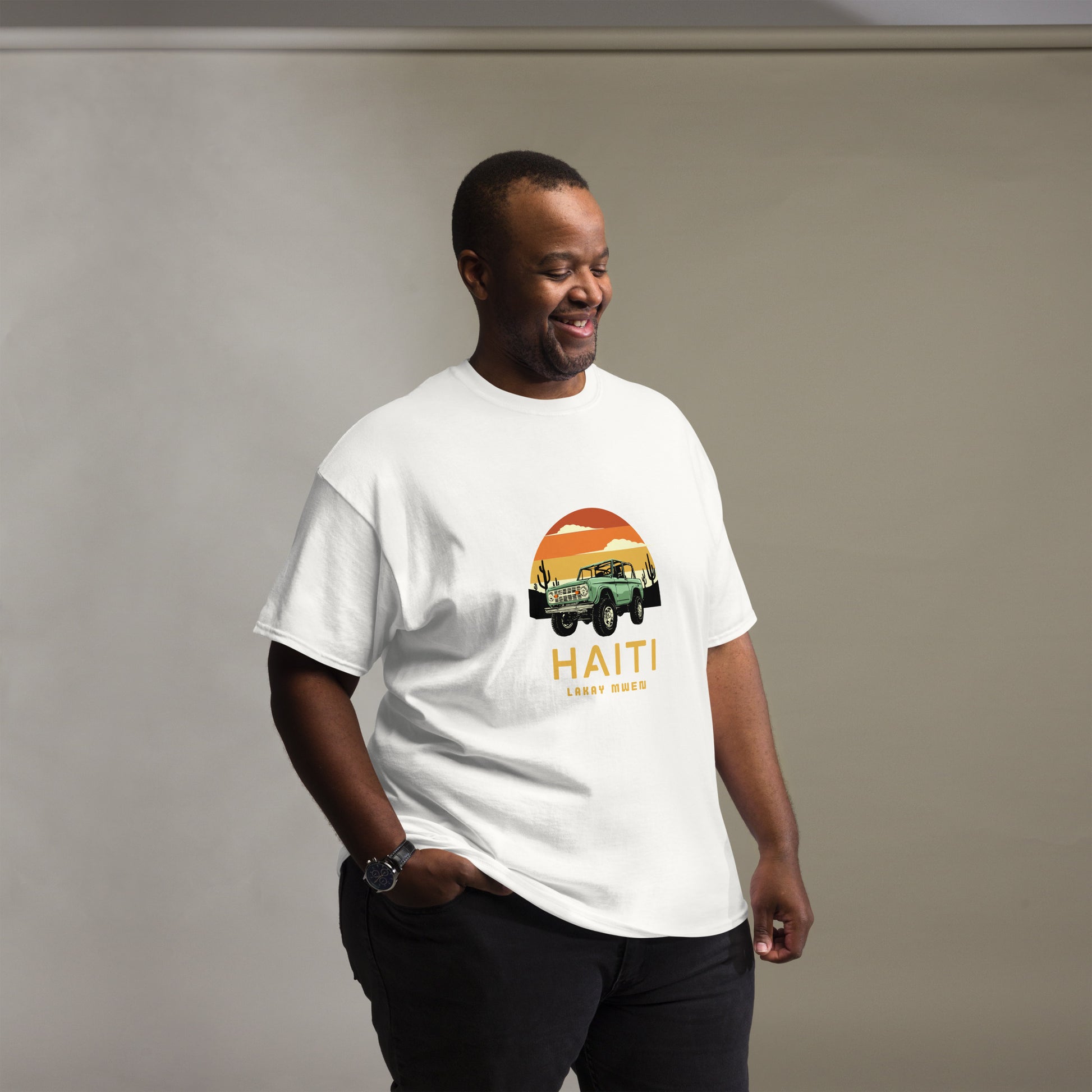 Male model standing with one hand in his pocket wearing XL Bella+Canvas 'Haiti Lakay Mwen' unisex T-shirt featuring a retro sunset and green vintage Jeep graphic