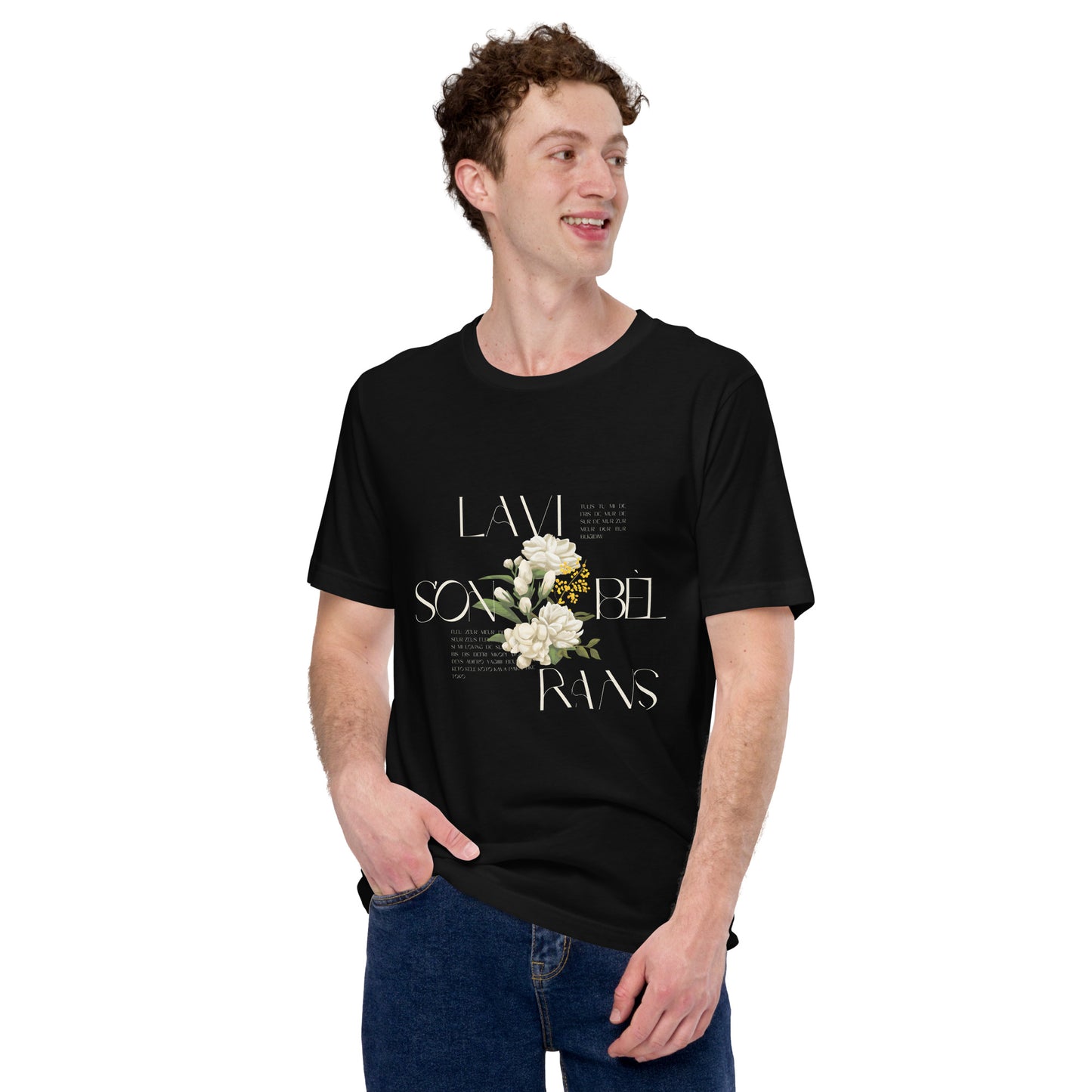 White male model wearing a black Bella+Canvas 'LAVI S'ON BÈL RANS' unisex T-shirt (front view) featuring cream text and a realistic white floral graphic. The man has short brown hair and is wearing blue jeans.