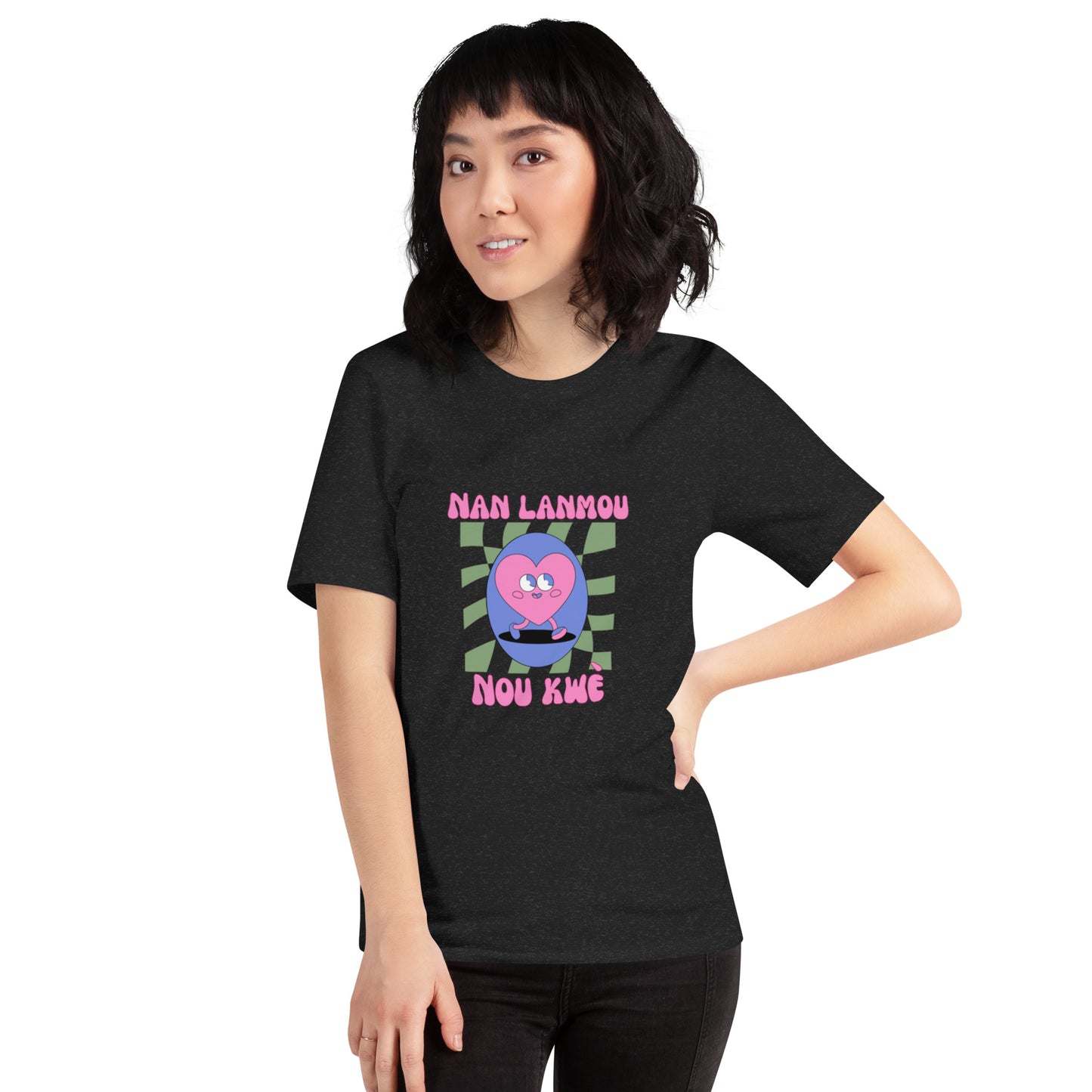 Asian woman wearing a black Bella+Canvas 'Nan Lanmou Nou Kwe' unisex T-shirt (front view) featuring a pink and blue abstract heart graphic with a smiley face and paint drip accents.