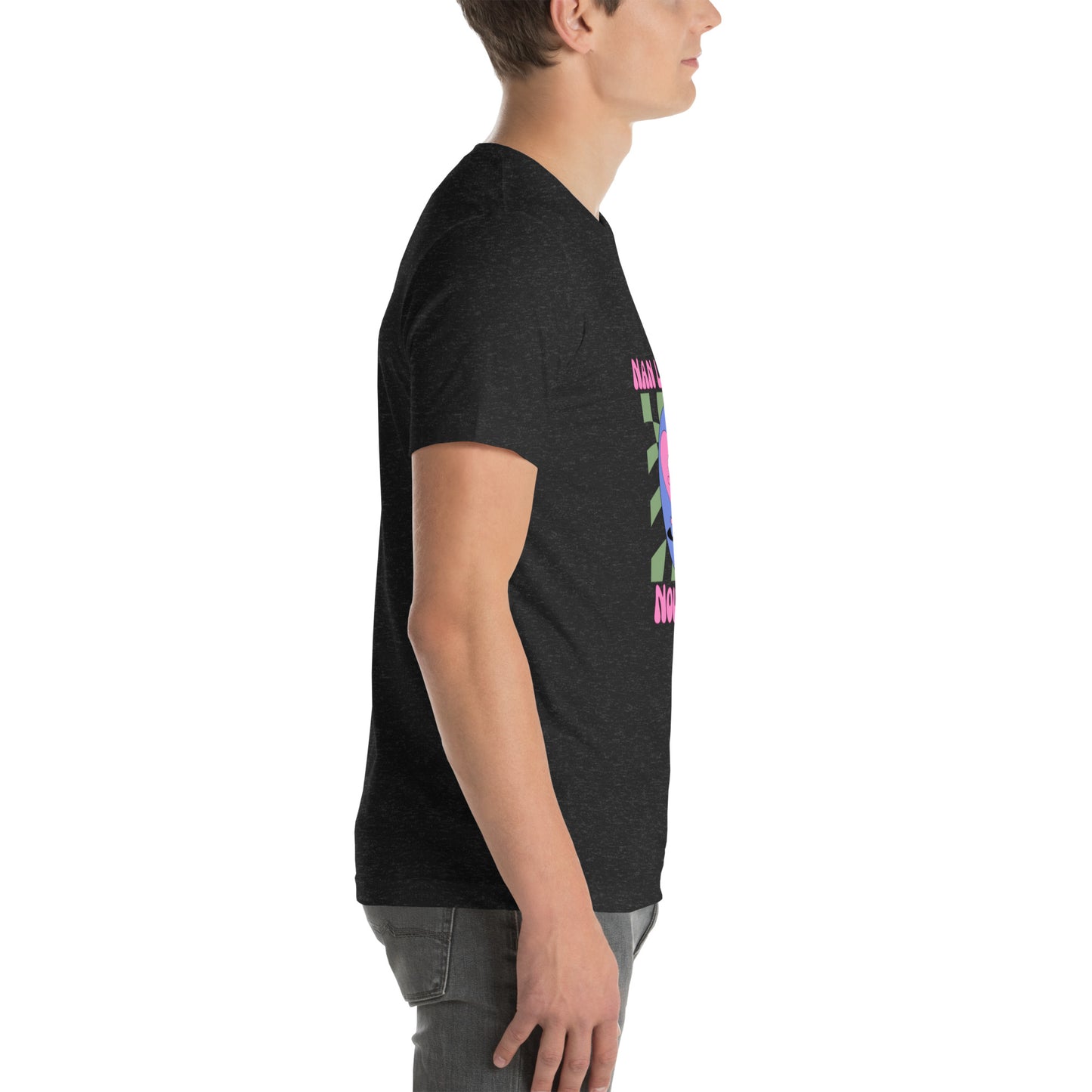 White man wearing a black Bella+Canvas 'Nan Lanmou Nou Kwe' unisex T-shirt (right side view) featuring a pink and blue abstract heart graphic with a smiley face and paint drip accents.