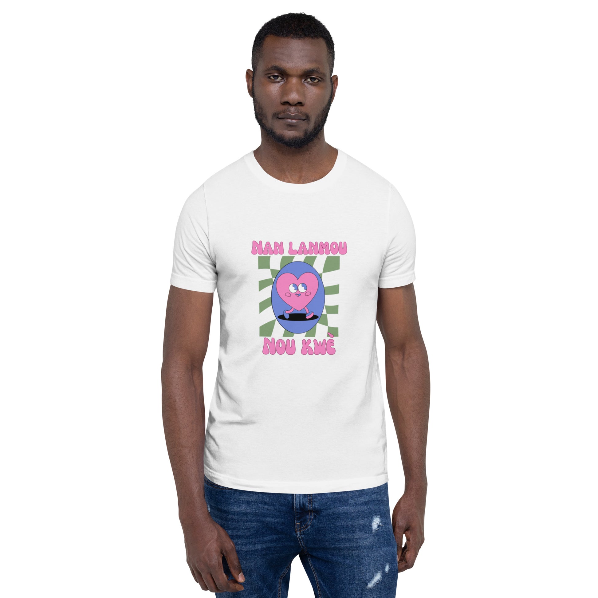Black man wearing a white Bella+Canvas 'Nan Lanmou Nou Kwe' unisex T-shirt (front view) featuring a pink and blue abstract heart graphic with a smiley face and paint drip accents.