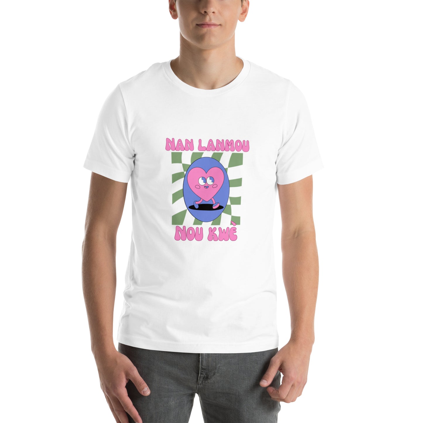 White man wearing a black Bella+Canvas 'Nan Lanmou Nou Kwe' unisex T-shirt (front view) featuring a pink and blue abstract heart graphic with a smiley face and paint drip accents.